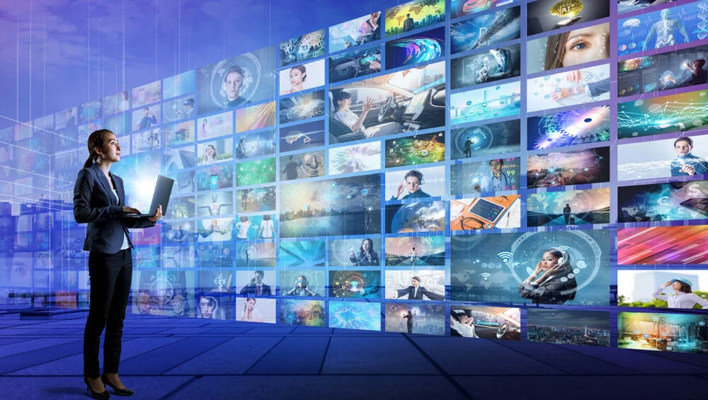 a woman standing in front of a large wall of monitors